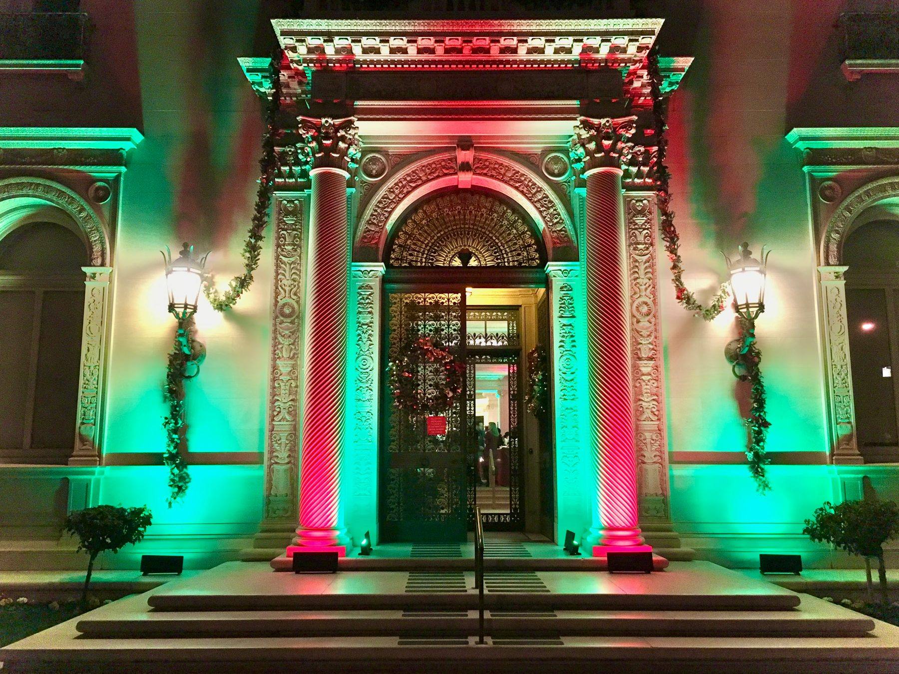 Flood Mansion facade lit in red and green for a holiday party